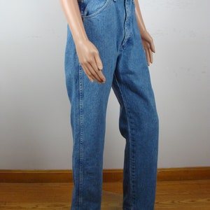 May include: Light blue denim jeans with a brown leather belt. The jeans have a classic straight-leg fit and a traditional five-pocket design. The belt is a medium brown color with a decorative cut-out pattern.