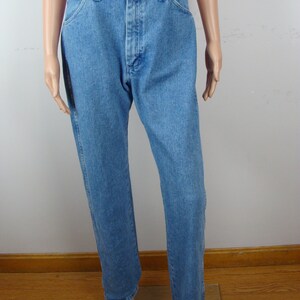 May include: Light blue denim jeans with a classic five-pocket design. The jeans have a button and zipper closure, belt loops, and a straight leg fit. The denim has a medium wash and a slightly faded appearance.
