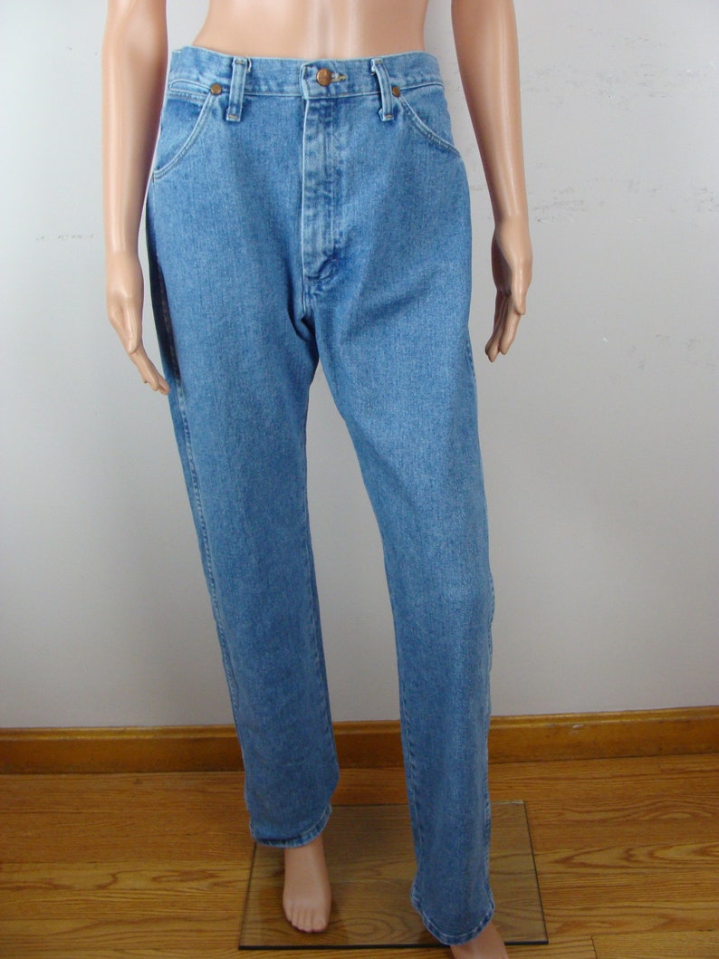 May include: Light blue denim jeans with a classic five-pocket design. The jeans have a button and zipper closure, belt loops, and a straight leg fit. The denim has a medium wash and a slightly faded appearance.