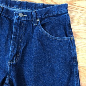 Op de afbeelding: Een donkerblauwe spijkerbroek met een knoopsluiting en &eacute;&eacute;n achterzak. De broek heeft een klassieke rechte pasvorm.