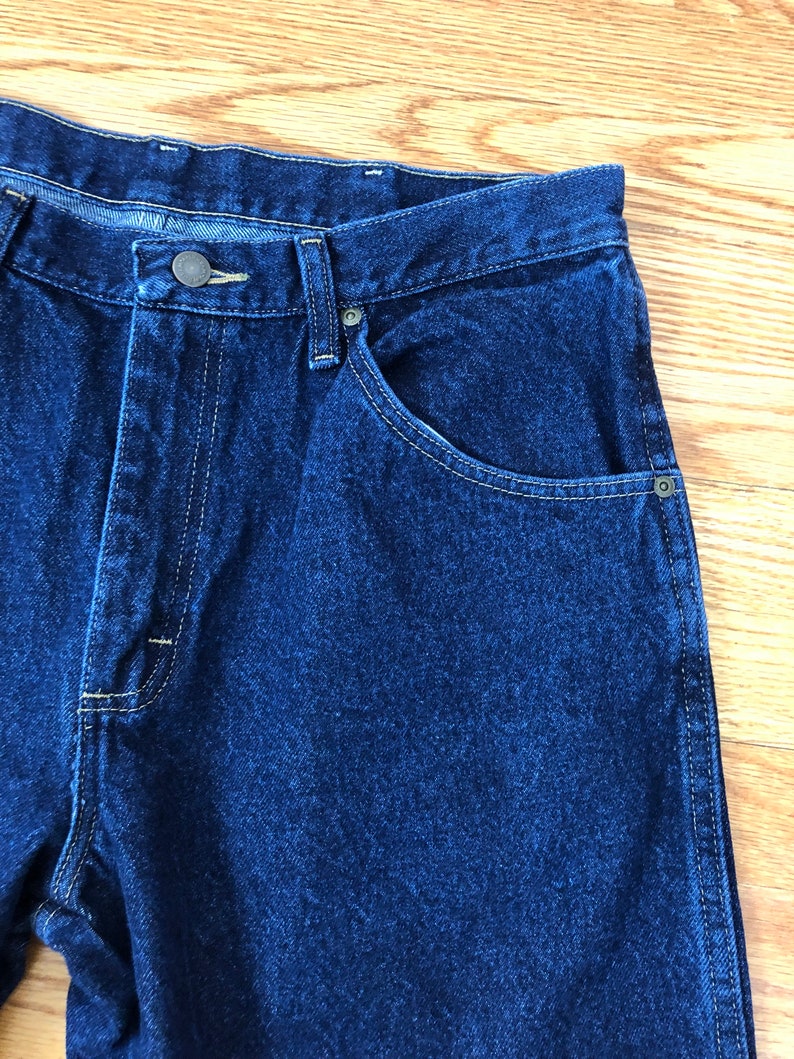 Op de afbeelding: Een donkerblauwe spijkerbroek met een knoopsluiting en &eacute;&eacute;n achterzak. De broek heeft een klassieke rechte pasvorm.