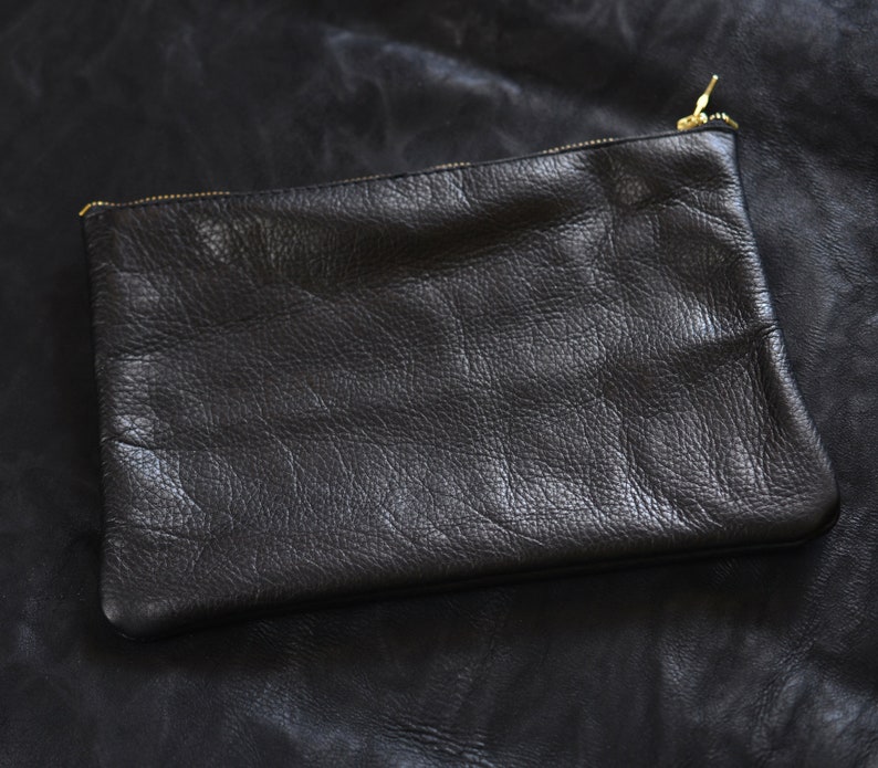 May include: A black leather clutch with a gold zipper.
