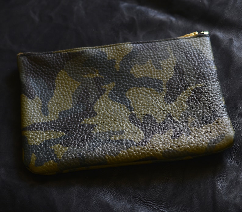 May include: A green, black, and brown camouflage patterned leather pouch with a gold zipper.