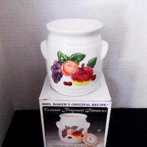 May include: White ceramic potpourri simmerer with a fruit design. The potpourri simmerer is in its original box, which reads "MRS. BAKER'S ORIGINAL RECIPE Ceramic Potpourri Simmerer".