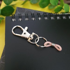 May include: A silver key chain with a silver hook and a pink rubber loop.