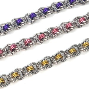 May include: Three silver chain bracelets with different colored accents. The top bracelet has purple accents, the middle bracelet has pink accents, and the bottom bracelet has gold accents.