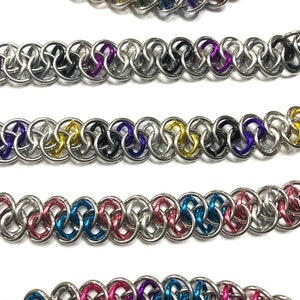 May include: Five different chainmail bracelets with alternating colored rings. The bracelets are made of silver metal with colored rings in rainbow, black and purple, gold and purple, pink and blue, and blue and purple.