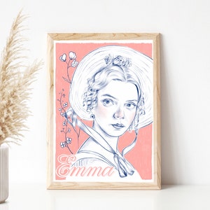 Puede incluir: Una impresión artística enmarcada que presenta un retrato de una mujer con un gorro y vestido blancos, con el nombre "Emma" en escritura cursiva. La obra de arte es en azul y blanco sobre un fondo rosa, en un marco de madera clara.