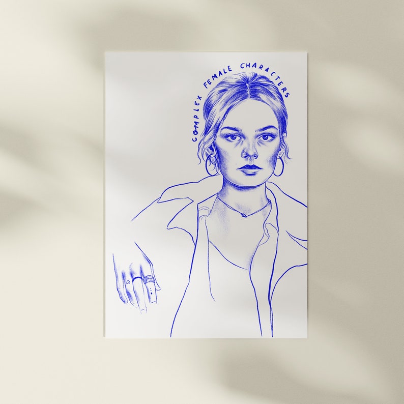 Op de afbeelding: Een blauwe lijntekening op wit papier toont een vrouw met de tekst "COMPLEX FEMALE CHARACTERS" boven haar hoofd. De vrouw draagt een ketting, oorringen en een overhemd met knopen. Haar hand rust op een oppervlak, met ringen aan haar vingers.