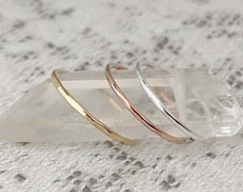 May include: Three thin hammered metal rings in gold, rose gold, and silver.