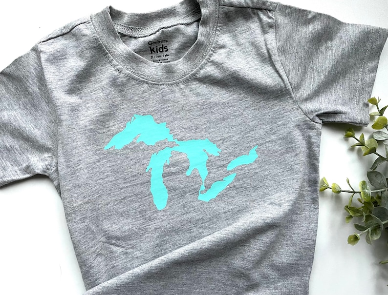May include: Grey short-sleeved t-shirt with a light blue outline of the Great Lakes on the front. The shirt has the text "Gerber Kids" on the tag.