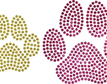May include: Two paw print designs, one in gold and the other in magenta, each composed of numerous small, sparkling rhinestones. The paw prints are set against a white background, creating a contrasting and eye-catching visual.