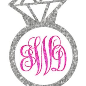 Könnte beinhalten: Ein silberner Glitzer-Ring mit einem pinkfarbenen Glitzer-Monogramm in der Mitte. Der Ring ist ein beliebtes Design für Hochzeiten, Verlobungen und andere besondere Anlässe.