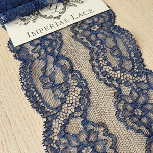 May include: Navy blue lace trim with a floral pattern. The lace is delicate and has a soft, flowing texture. The trim is perfect for adding a touch of elegance to any project.