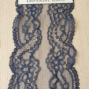 May include: Navy blue lace trim with a delicate floral pattern. The lace is shown folded in half, with the text "IMPERIAL LACE" visible on a white label.