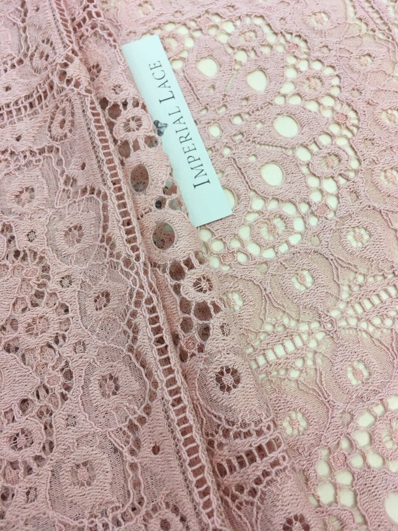 May include: Close-up of a pale pink lace fabric with a white label that reads "Imperial Lace".