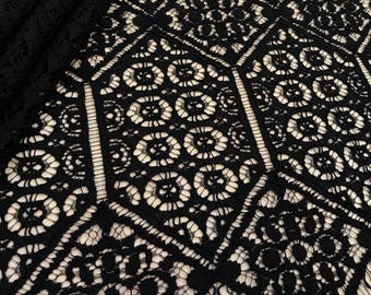 Peut inclure: Tissu de dentelle noire avec un motif géométrique. Le tissu a un bord festonné et est étiqueté "Imperial Lace".