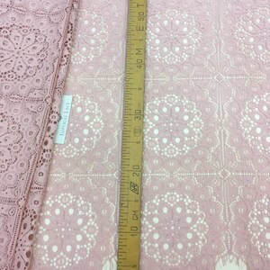 May include: Pink lace fabric with a delicate floral pattern. The fabric is measured with a ruler showing 30 inches.