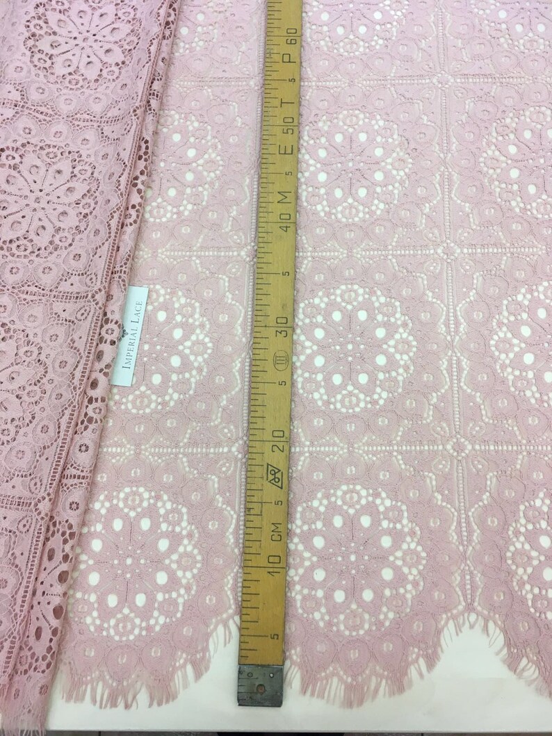 May include: Pink lace fabric with a delicate floral pattern. The fabric is measured with a ruler showing 30 inches.