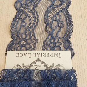 May include: Navy blue lace trim with a delicate floral pattern. The lace is shown on a wooden surface with a card that reads "Imperial Lace".