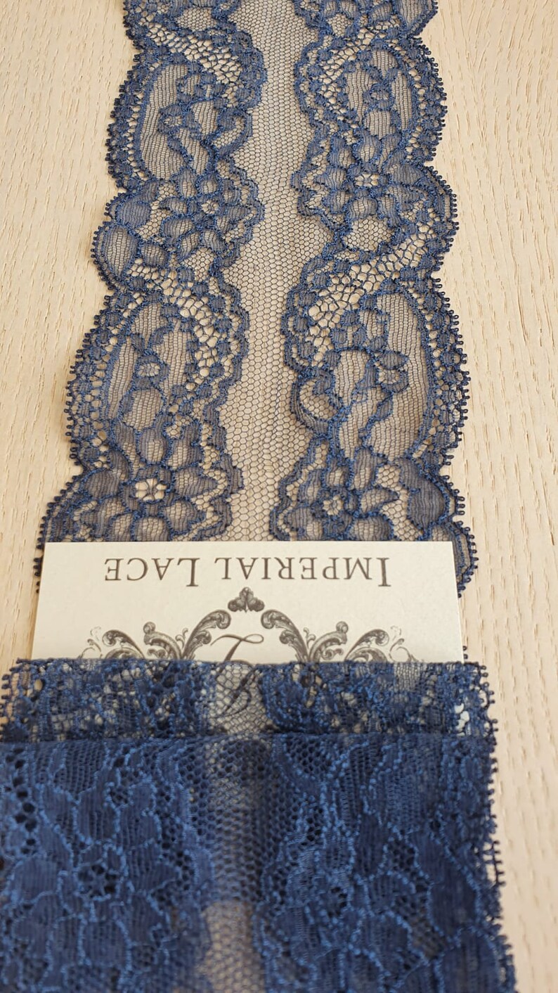 May include: Navy blue lace trim with a delicate floral pattern. The lace is shown on a wooden surface with a card that reads "Imperial Lace".