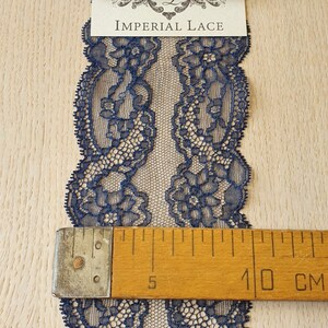 May include: Navy blue lace trim with a floral pattern. The lace is approximately 10 cm wide.