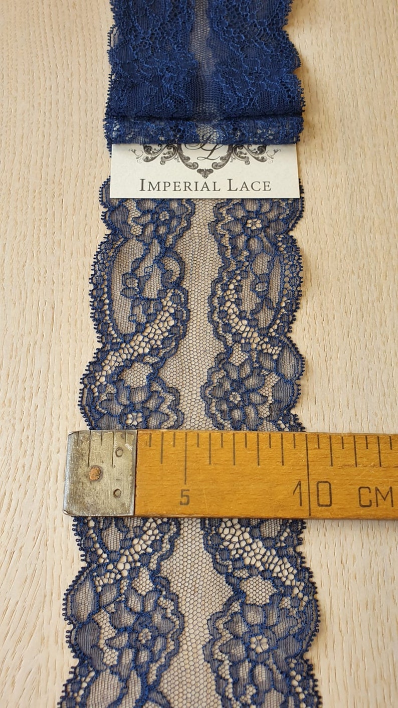 May include: Navy blue lace trim with a floral pattern. The lace is approximately 10 cm wide.