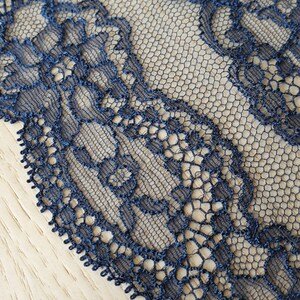 May include: Dark blue lace trim with a delicate floral pattern. The lace is made of a fine mesh fabric and has a scalloped edge.