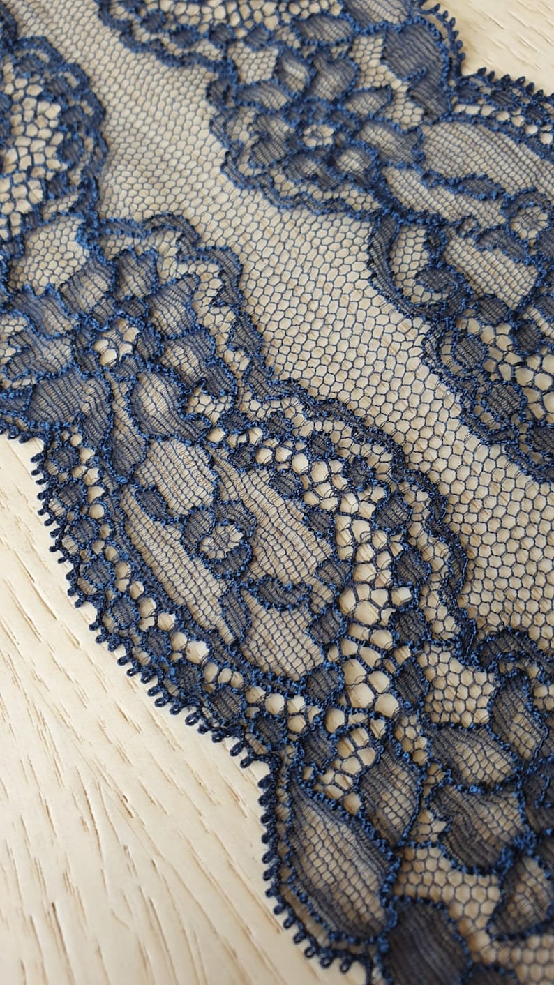 May include: Dark blue lace trim with a delicate floral pattern. The lace is made of a fine mesh fabric and has a scalloped edge.