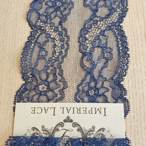 May include: Navy blue lace trim with a delicate floral pattern. The lace is shown folded in half and has a label that reads "Imperial Lace".