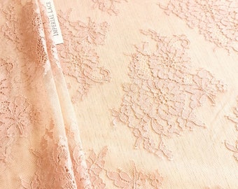 May include: Close-up of a delicate, light pink lace fabric with floral patterns. The fabric is semi-sheer, with a soft texture and intricate detailing. The tag reads "IMPERIAL LACE".