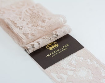 May include: A close-up of a pale pink lace trim with a brown card that reads "IMPERIAL LACE french lace dealer".