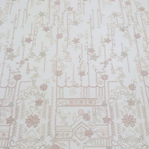 May include: White beaded fabric featuring a delicate floral pattern and geometric shapes. The fabric has a subtle shimmer and is ideal for adding a touch of elegance to any project.