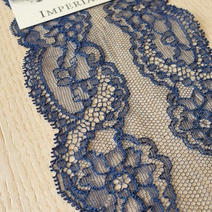 May include: Navy blue lace trim with a delicate floral pattern. The lace is shown on a wooden surface with a tag that reads "Imperial Lace".