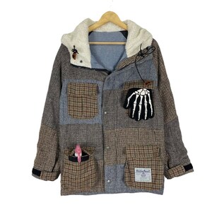 May include: A multi-coloured patchwork jacket with a fleece-lined hood. The jacket has a skeleton hand patch on the front and a small pocket with the text "Harris Tweed" on the bottom right.