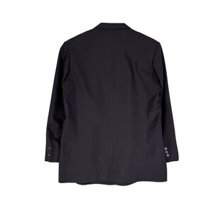 Op de afbeelding: Zwarte blazer, gezien vanaf de achterkant, met een klassiek ontwerp en lange mouwen. Knopen sieren de manchetten en de voorkant. De blazer tegen een witte achtergrond benadrukt de elegante uitstraling en formele stijl.