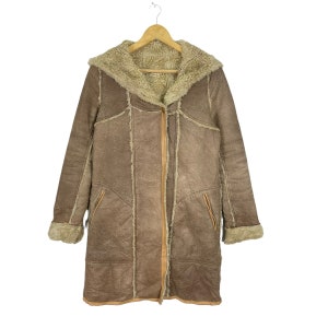 May include: A brown faux fur hooded coat with a zipper closure. The coat has a shearling lining and a brown leather trim.