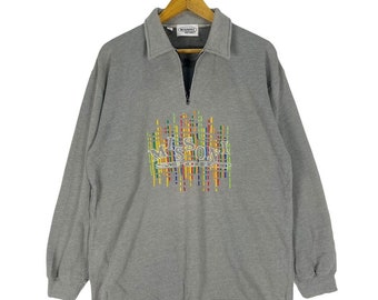 Puede incluir: Sudadera gris de manga larga con cierre de cremallera de media cremallera y un logotipo de Missoni Sport de colores bordado en la parte delantera.