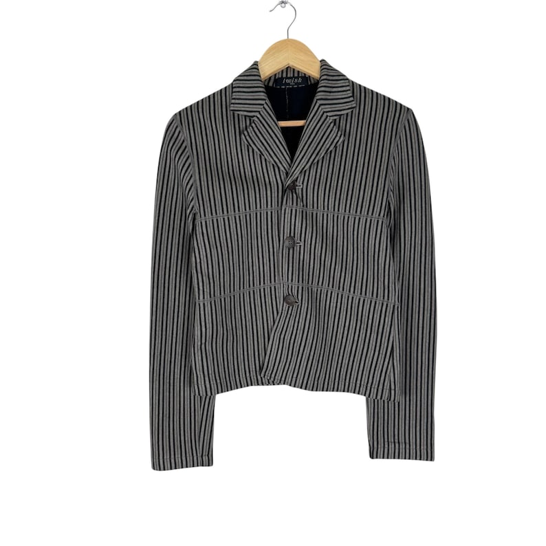 Op de afbeelding: Een grijs en zwart gestreepte blazer met een reverskraag en drie knopen. De jas hangt aan een houten hanger tegen een witte achtergrond. De blazer heeft een getailleerde pasvorm en lange mouwen.