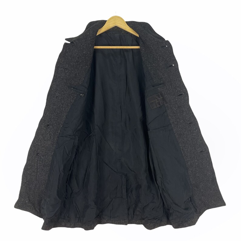 May include: A dark gray wool coat with a black lining. The coat has a double breasted closure and a collar.