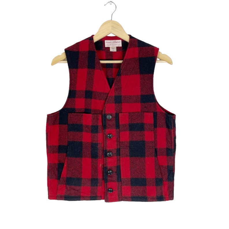 Op de afbeelding: Rood en zwart geruit flanellen vest met knoopsluiting en twee grote zakken. Het vest heeft een "Tigon Garment" label.