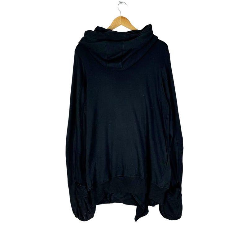 May include: Black hooded sweatshirt with a long, flowing design. The sweatshirt has a large hood and a relaxed fit.