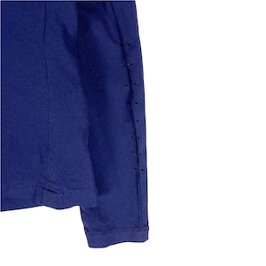 Puede incluir: Una camisa de manga larga azul marino con una fila de peque&ntilde;os agujeros en la manga derecha.