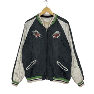 May include: Black quilted bomber jacket with white satin sleeves and green and white striped trim. The jacket features embroidered Japanese-style designs on the front.