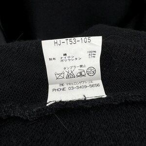 May include: A white tag with black text and symbols. The tag has the text "HJ-T53-105" at the top. The tag also has the text "綿 100% ポリウレタン 83% 17%" and "タンブラー禁止" in Japanese. The tag also has a phone number: "PHONE 03-3409-5656".