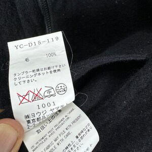 K&ouml;nnte beinhalten: Ein schwarzes Pflegeetikett f&uuml;r Kleidung mit wei&szlig;em Text. Das Etikett lautet "YC-D15-119", "100%", "毛", "タンブラー乾燥はお避け下さい", "クリーニングネットを使用して下さい", "1001", "(株)ヨウジ", "東京都品川", "2-2-", "取扱い上の注意", "ドライ", "セキス", "CE VETEMENT PEUT PELUCHER AL USAGE", "MANIPULER AVEC PRECAUTION", "FABRIC MAY PILE WITH FREQUENT", "HANDLE WITH CARE", "の特性上、着用時などの", "下さい", "みを生じる恐れがあり", "モト".