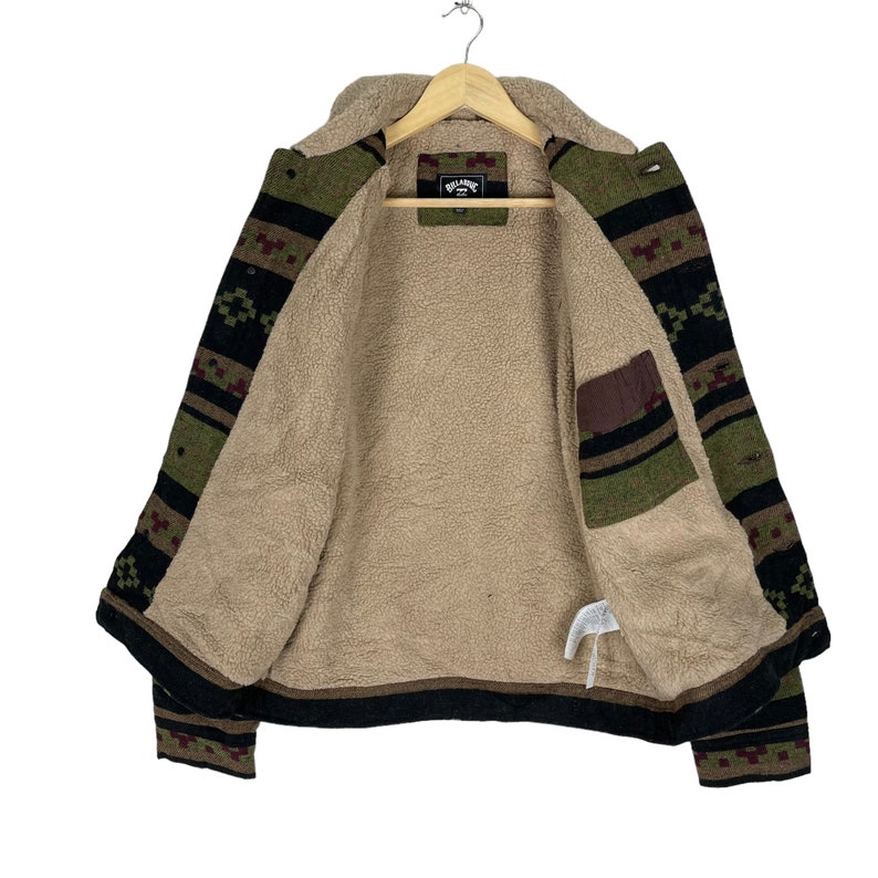 May include: A brown, black and green patterned jacket with a fleece lining. The jacket has a button closure and two pockets. The brand name "Billabong" is visible on the inside label.