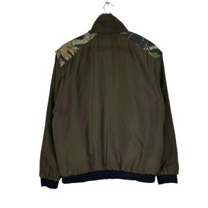 May include: A dark green jacket with a camouflage pattern on the shoulders and a black ribbed waistband.