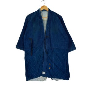 May include: A dark blue denim jacket with a quilted pattern and a tie closure. The jacket has a traditional Japanese style and features a small label with Japanese characters.