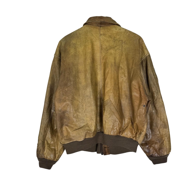 May include: A vintage brown leather bomber jacket with a classic collar and ribbed cuffs and hem. The jacket has a distressed appearance with variations in color, showcasing a worn, aged aesthetic. The back view highlights the jacket's design and construction.